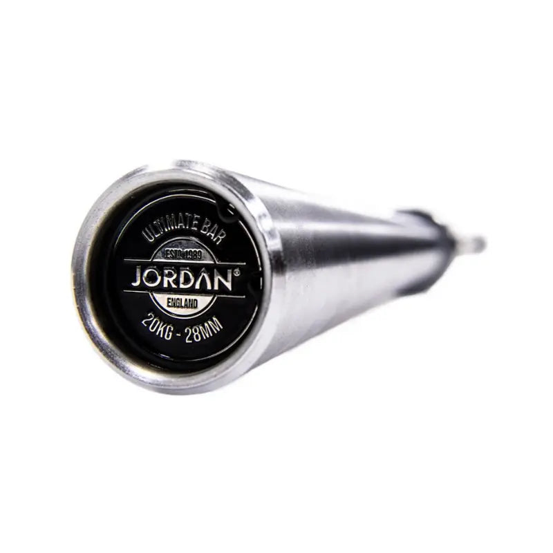 Close-up of the end of a silver Jordan Ultimate Olympic Bar—competition standard, 20kg, 28mm—showing a black cap with the brand name. The barbells durable shaft fades out of focus.