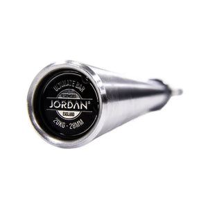 Close-up of the end of a silver Jordan Ultimate Olympic Bar—competition standard, 20kg, 28mm—showing a black cap with the brand name. The barbells durable shaft fades out of focus.