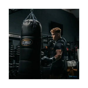 The Carbon Claw Pro FX-7 Series 4FT Heavy Punch Bag (45kg, foam padded) in black synthetic leather with chain attachments and logo is designed for boxing training, shown hanging against a plain white background.