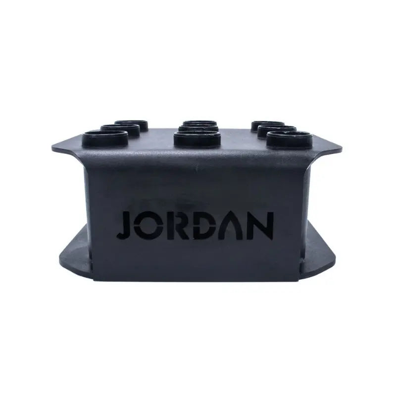 The JORDAN Olympic Bar Holder by Jordan is a black, rectangular rack with nine vertical slots for organizing Olympic bars upright, featuring the brand name cut out on the side.