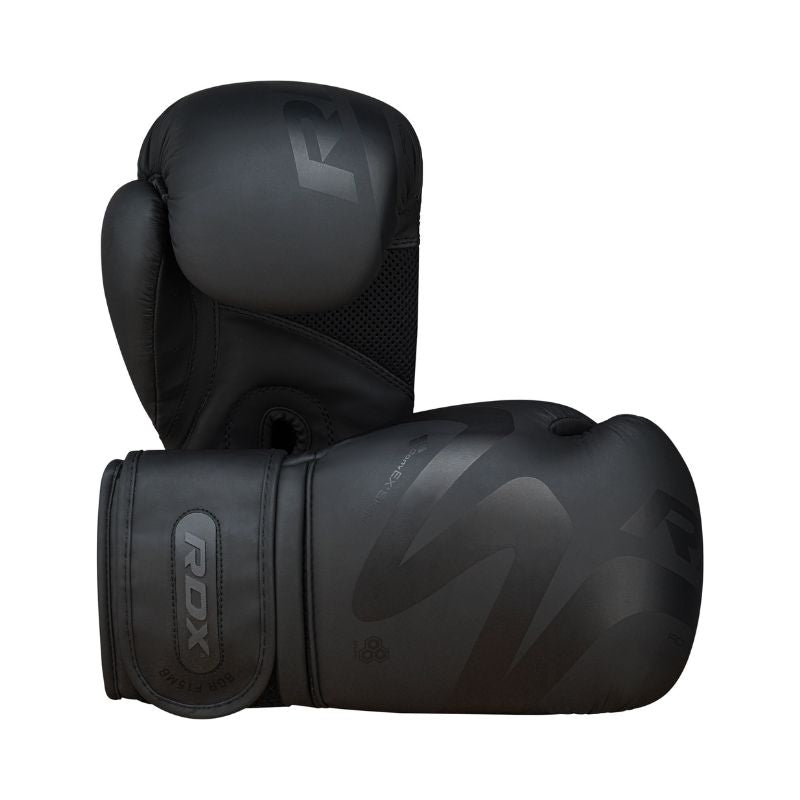 A pair of black RDX boxing gloves, with one glove standing upright and the other lying on its side, showing the Velcro strap and subtle branding details.