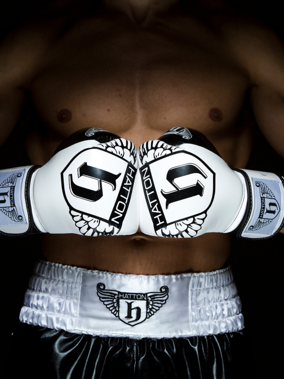Close-up of a person wearing white boxing gloves and trunks with 'Haddon' branding.