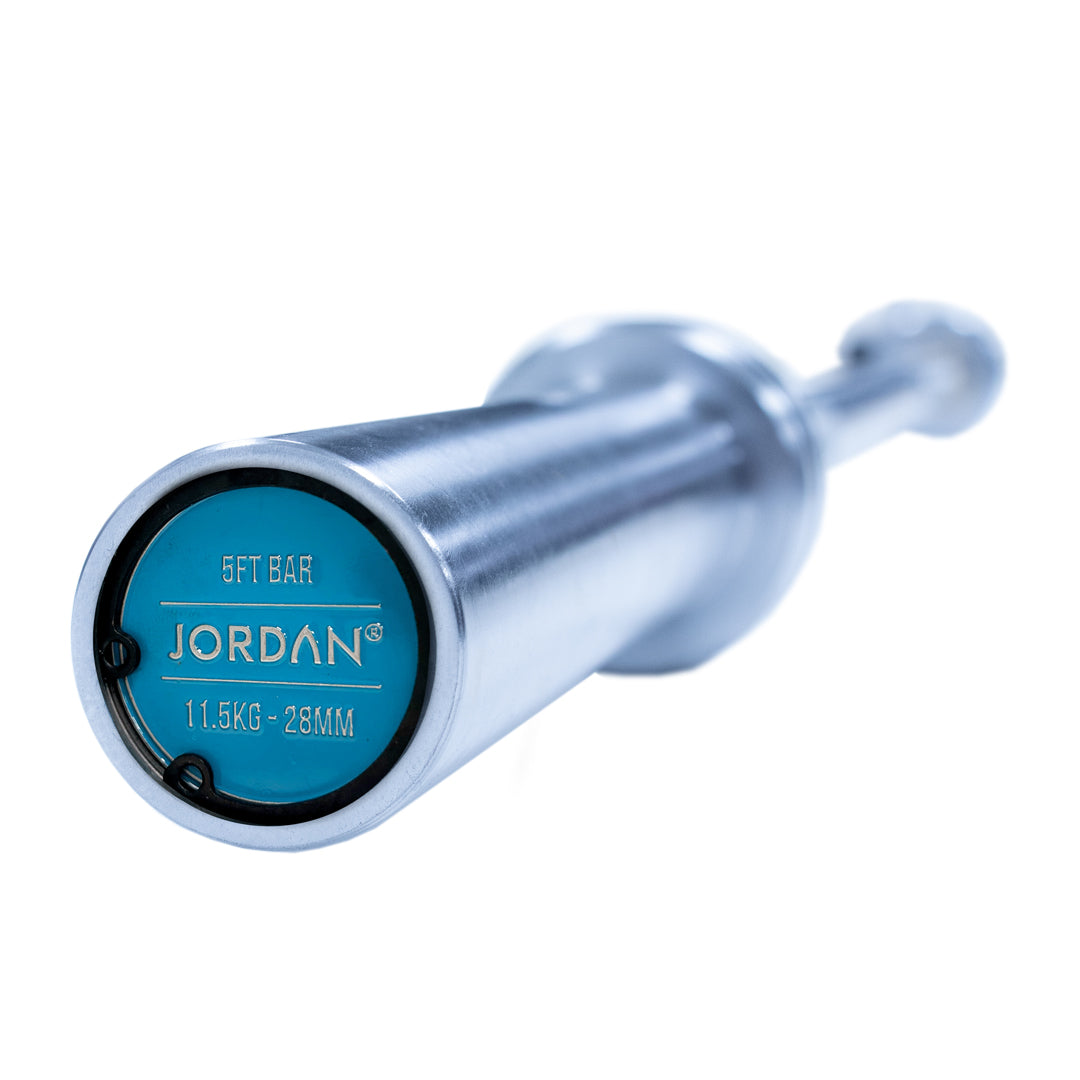 Close-up of a barbell end reveals a blue cap with JORDAN in white, marked 21.5KG - 32MM. The JORDAN Steel Series Straight Olympic Bars With Bearings feature a shiny silver finish and durable build, perfect for versatile athlete training.