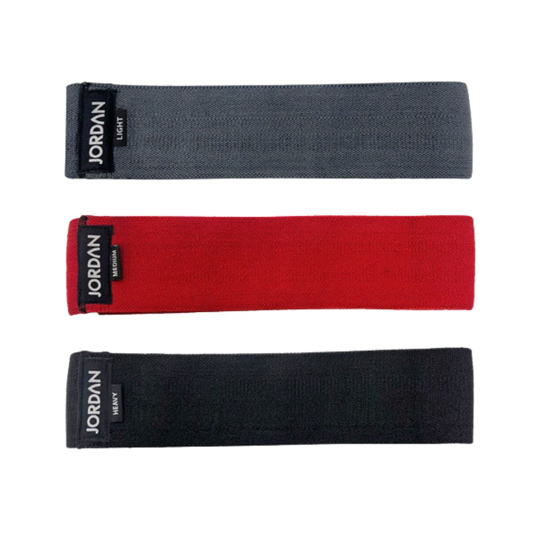 The JORDAN Fabric Resistance Band is red with Jordan and Medium on a black label, offering a smooth texture and moderate elasticity. Its durable design makes it perfect for fitness and strength training, providing versatile workout options.
