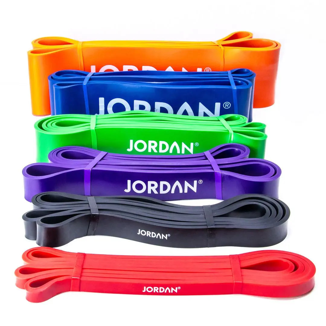 Five resistance bands in orange, blue, green, purple, black, and red, stacked in a row. Each band displays the brand name JORDAN in white letters.