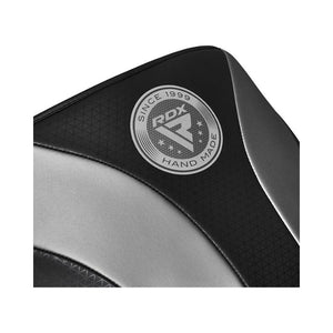 Close-up of a black and silver padded surface with a circular "RDX Hand Made Since 1999" logo printed on it. The material has a textured and smooth finish.