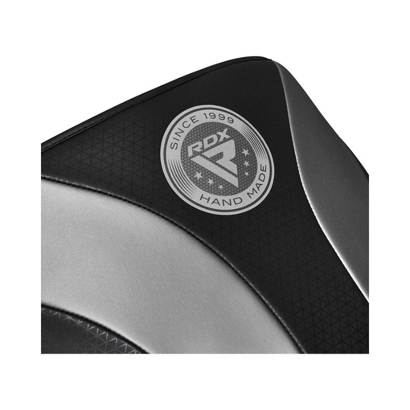 Close-up of a black and silver padded surface with a circular "RDX Hand Made Since 1999" logo printed on it. The material has a textured and smooth finish.
