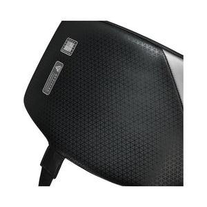 Close-up of a black textured surface with a subtle triangular pattern, featuring a small square chip and a rectangular label with text, and a strap attached at the bottom.