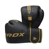 A pair of black RDX boxing gloves with gold accents and branding, one glove standing upright and the other lying on its side, displaying the wrist strap and logo.