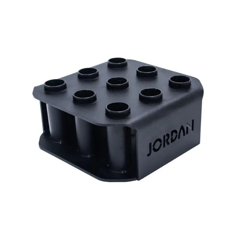 The JORDAN Olympic Bar Holder by Jordan is a black, rectangular rack with nine vertical slots for organizing Olympic bars upright, featuring the brand name cut out on the side.