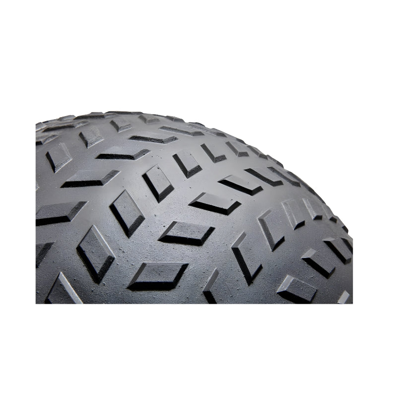 Close-up view of the tread pattern on a black slam ball showing a geometric, diamond-shaped design on a curved surface against a white background.