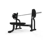 The JORDAN Olympic Flat Bench by Jordan is a black and gray UK-built commercial weight bench with a barbell and weights, ideal for upper-body strength training and Olympic Flat Bench press exercises, shown on a white background.