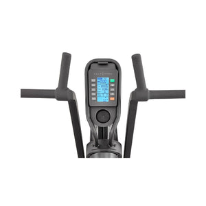 Close-up of a fitness machine's digital display and handlebars. The screen shows workout information such as time, distance, calories, and pulse, with multiple buttons below for control. The handles are padded and angled outward.