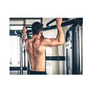 Man performing pull-ups on a pull-up bar in a gym.