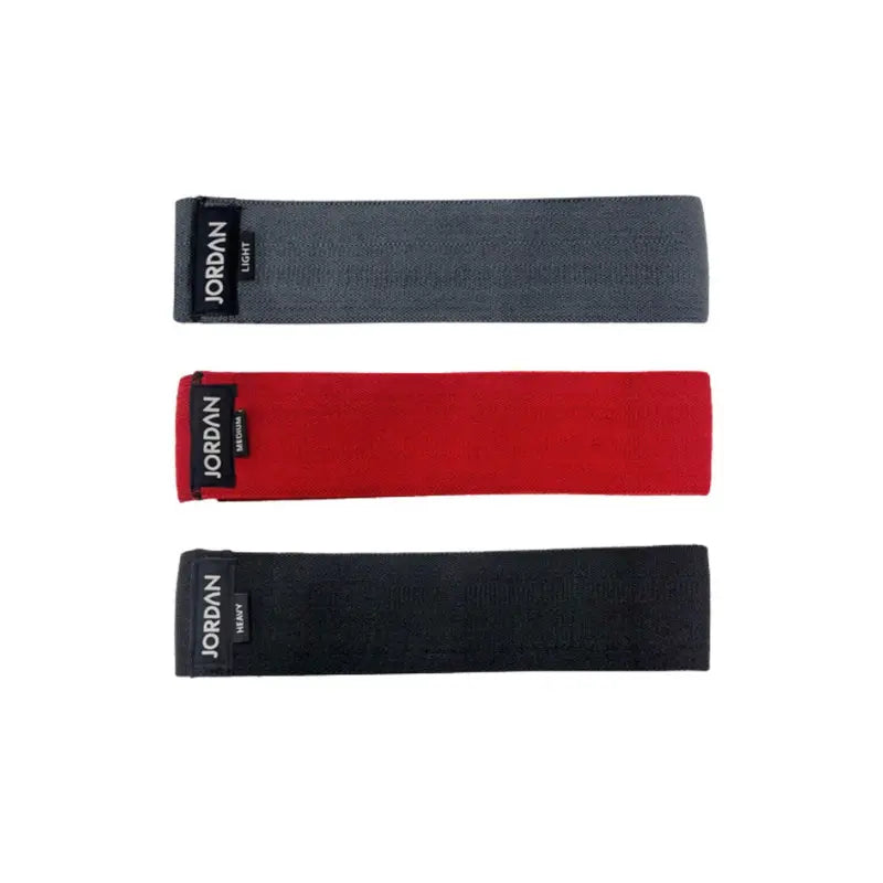 The JORDAN Fabric Resistance Band is a non-slip booty band for squats, lunges, and glute workouts. Shown in red with a black Jordan Medium label against a white background.