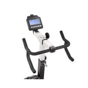 Close-up of a stationary exercise bike’s handlebars and digital display screen, showing workout data such as time, speed, and calories. The bike has a silver and black color scheme against a white background.
