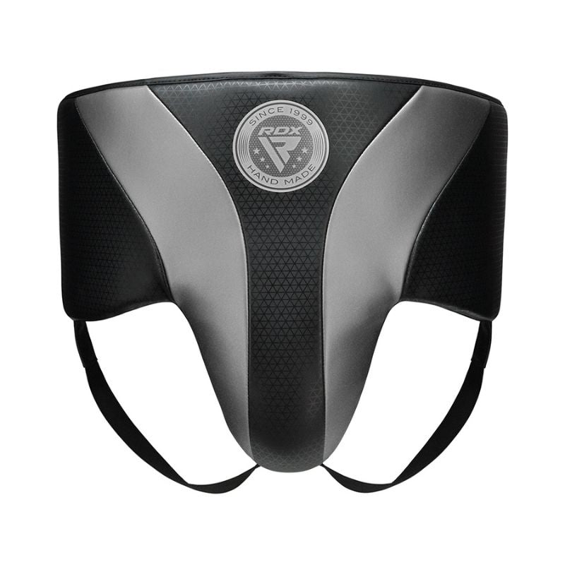 A black and gray protective groin guard with the "RDX" logo in the center, featuring two leg straps and designed for sports or martial arts use.
