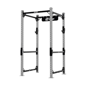 The Exigo X70 Compact Power Rack by Exigo is a gray and black metal rack with multiple holes for adjustable attachments, safety bars, and a top pull-up bar—ideal for commercial strength or any home gym setup.