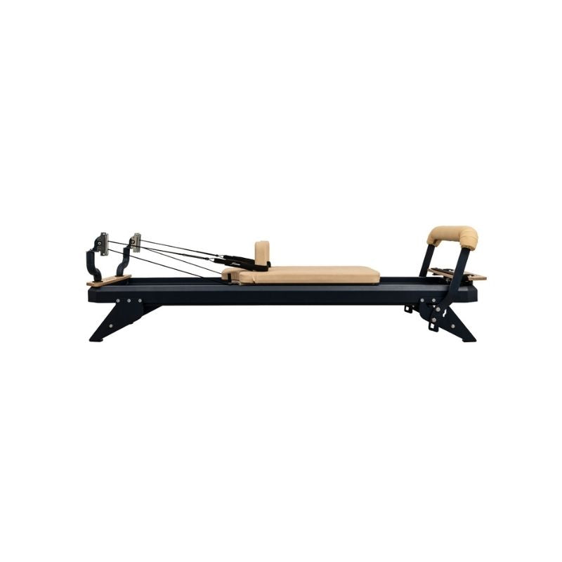 The HEGREN TALMA 62 Pilates Reformer by Hegren, featuring a black and beige padded platform, adjustable ropes, and headrest, is shown from the side. Studio-grade steel frame. Fast UK delivery available.