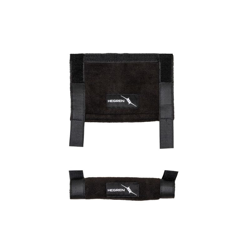 Two black fabric HEGREN Pilates Strap Comfort Covers by Hegren are shown: a rectangular padded cover with Velcro and two vertical straps on top, and a cylindrical strap cover below, both offering comfort and protection.