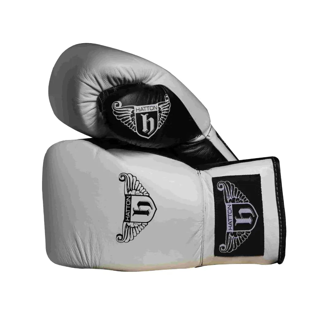 The Hatton Boxing Lace Up Gloves from Hatton, crafted in white and black leather, feature intricate shield and wings logo designs on the wrist. These gloves are perfect for sparring, displayed to show both front and thumb sides.