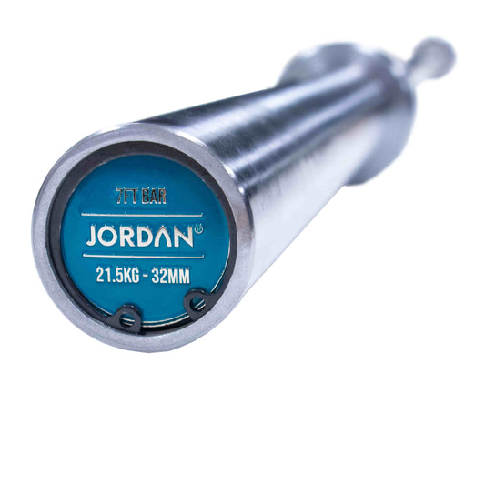 Close-up of a barbell end reveals a blue cap with JORDAN in white, marked 21.5KG - 32MM. The JORDAN Steel Series Straight Olympic Bars With Bearings feature a shiny silver finish and durable build, perfect for versatile athlete training.
