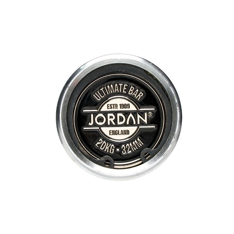 Top view of the round, silver and black end cap on the Jordan Ultimate Olympic Bars—Men’s & Women’s Competition-Standard Barbells (15kg/20kg)—built for rigorous use and labeled “Ultimate Bar, ESTD 1989, Jordan, England, 20KG - 32MM.”.