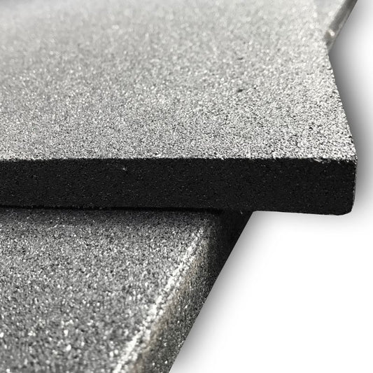 Close-up of two MYO Strength Rubber Black Tiles (1000mm x 1000mm x 20mm) stacked at an angle, showing their textured surface and smooth edges—ideal as durable gym flooring or for impact protection. Brand: MYO Strength.