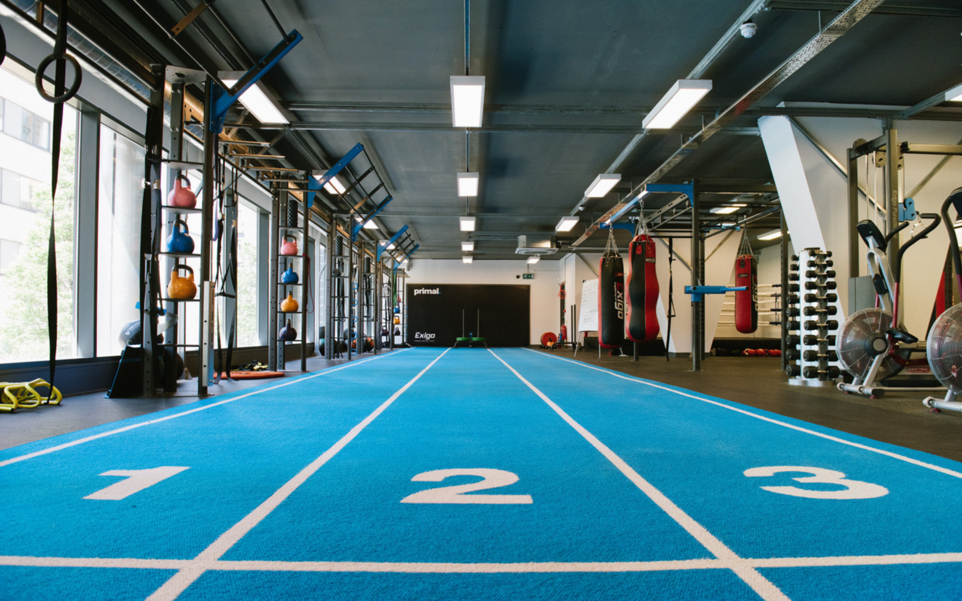 Gym interior with blue running track and various fitness equipment.