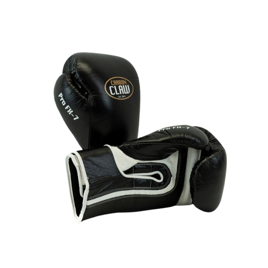 A pair of Carbon Claw Pro FX-7 Series Sparring Gloves in black and white genuine leather—one upright, one flat on a white background. Featuring ergonomic fit and wrist support, ideal for sparring sessions.
