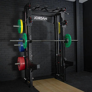 The JORDAN -J75 Cable Rack in black is a versatile gym power rack with barbells and weight plates on both sides. It features storage for weights and equipment, making it ideal for strength training exercises. The top arch is labeled Jordan.
