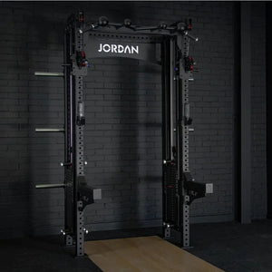 The JORDAN -J75 Cable Rack in black is a versatile gym power rack with barbells and weight plates on both sides. It features storage for weights and equipment, making it ideal for strength training exercises. The top arch is labeled Jordan.