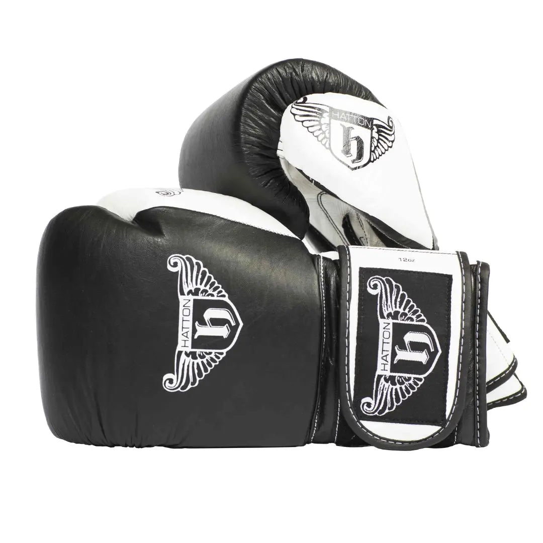 HATTON BOXING Velcro Sparring Gloves Leather, featuring the Hatton logo and a stylized H. These sleek black-and-white gloves include intricate white detailing, perfectly positioned for any boxing routine.