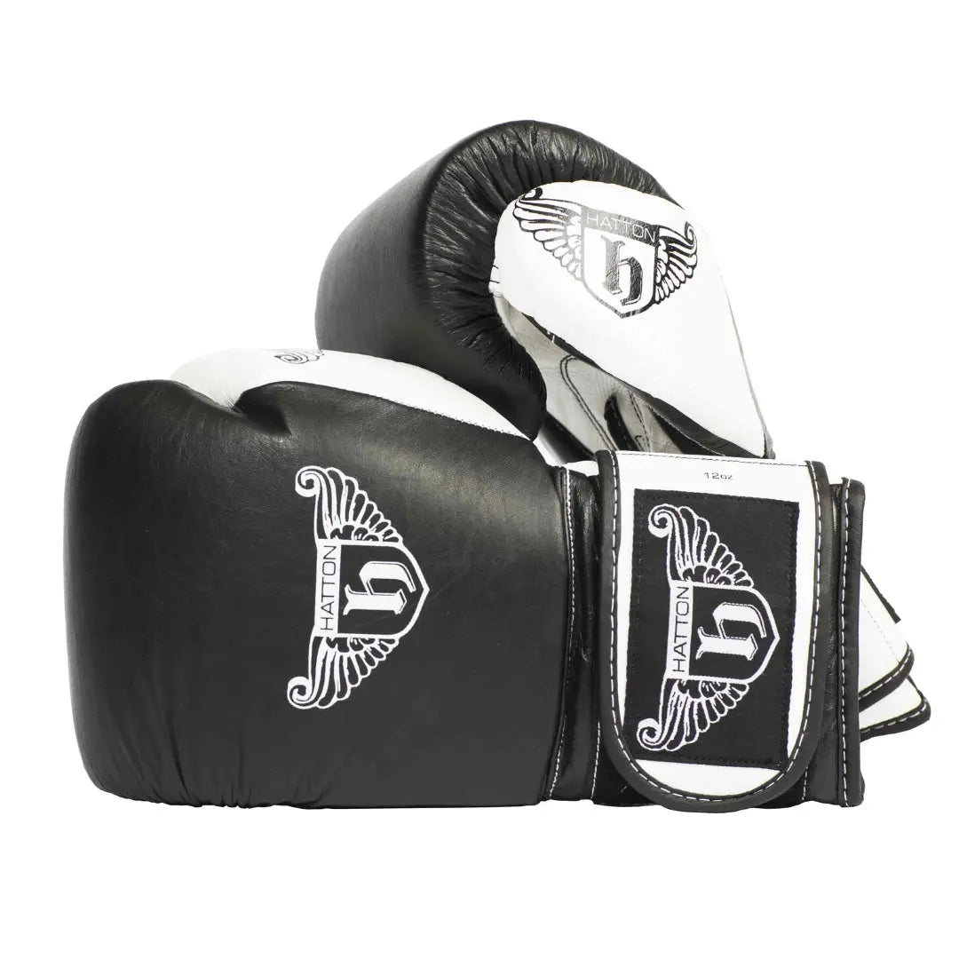 HATTON BOXING Velcro Sparring Gloves Leather, featuring the Hatton logo and a stylized H. These sleek black-and-white gloves include intricate white detailing, perfectly positioned for any boxing routine.