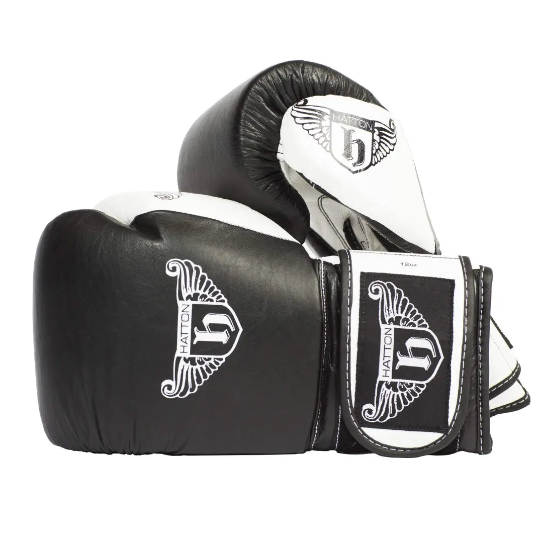 HATTON BOXING Velcro Sparring Gloves Leather, featuring the Hatton logo and a stylized H. These sleek black-and-white gloves include intricate white detailing, perfectly positioned for any boxing routine.