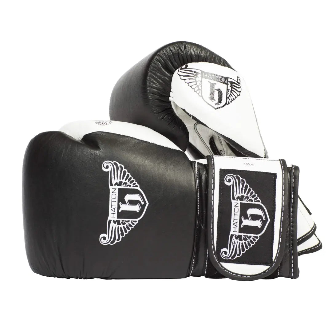HATTON BOXING Velcro Sparring Gloves Leather, featuring the Hatton logo and a stylized H. These sleek black-and-white gloves include intricate white detailing, perfectly positioned for any boxing routine.