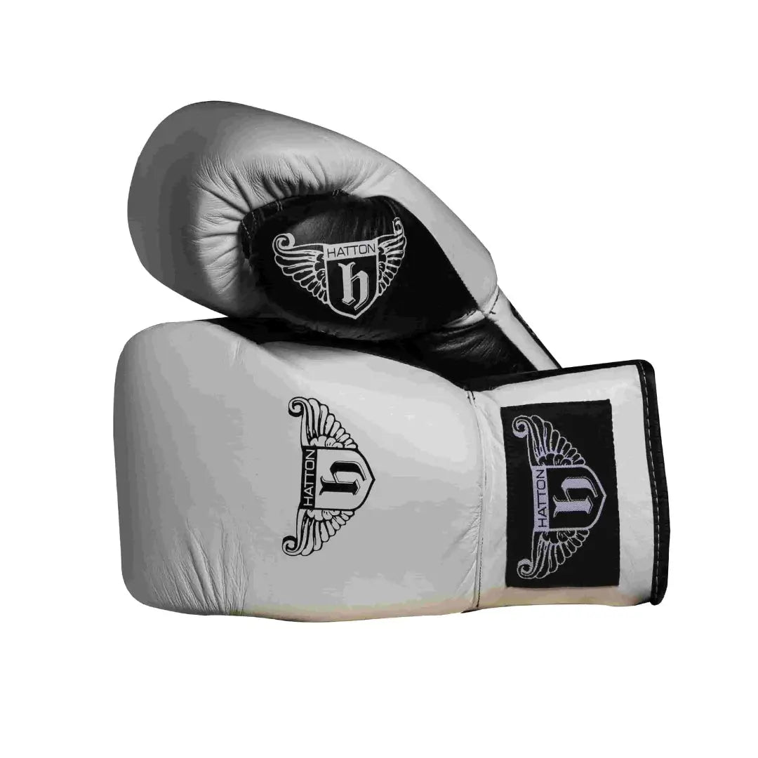 The Hatton Boxing Lace Up Gloves from Hatton, crafted in white and black leather, feature intricate shield and wings logo designs on the wrist. These gloves are perfect for sparring, displayed to show both front and thumb sides.